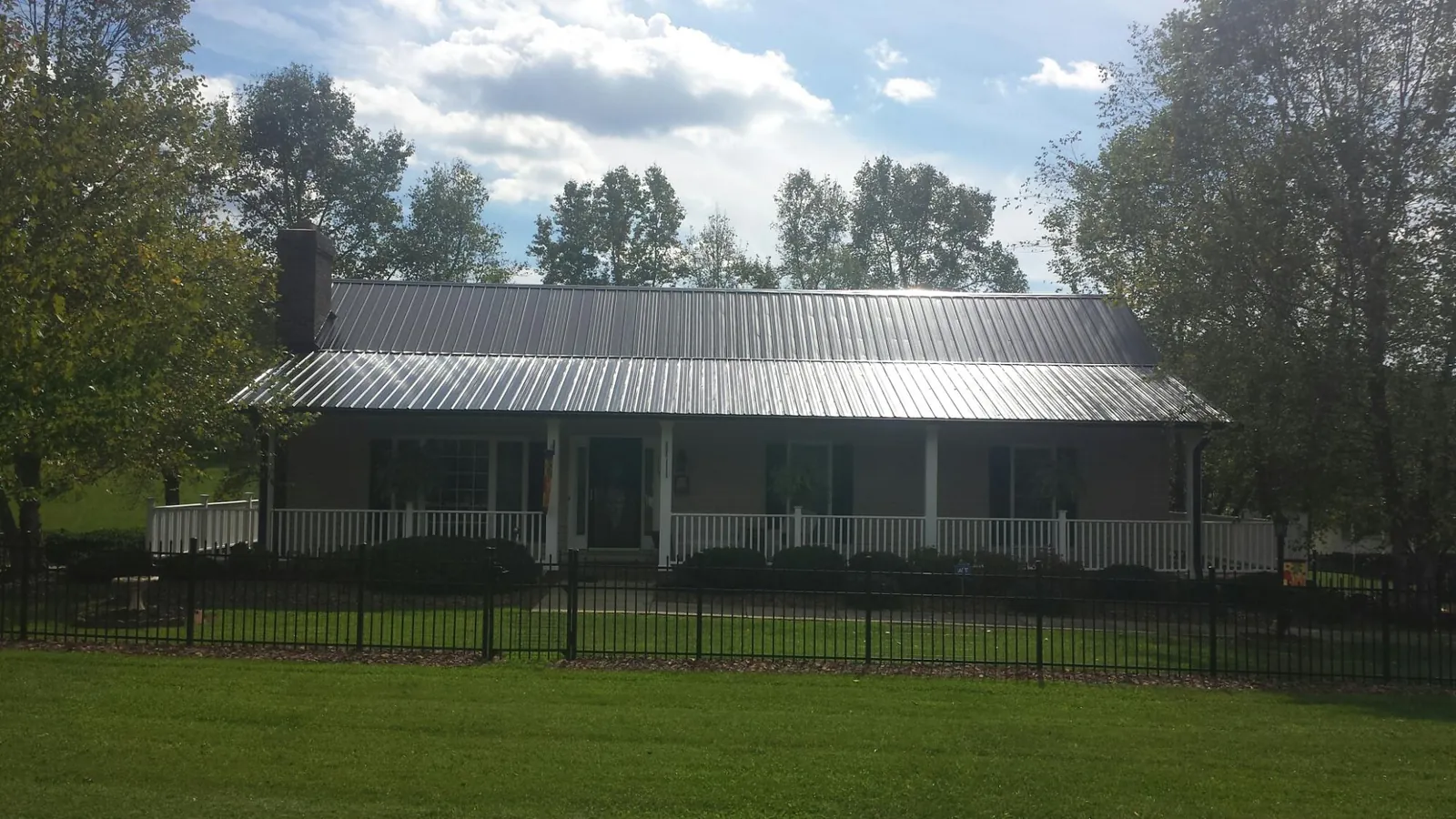 Gray metal roof on a brick ranch with a full width front porch — Gutter Guard Installation work by our crew in Hillsdale